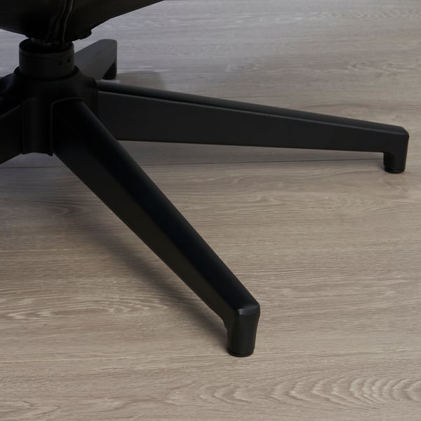 Close-up of sturdy black leather footstool base on wooden floor.
