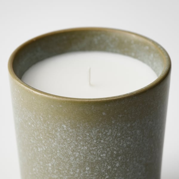 Cylindrical candle in textured green holder, unlit wick in centre, elegant & rustic design.