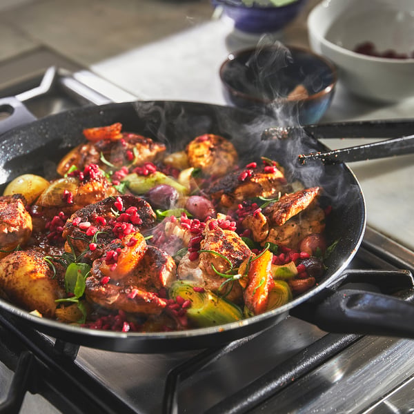 Frying pan cooking chicken and veg. Steam rising, non-stick.
