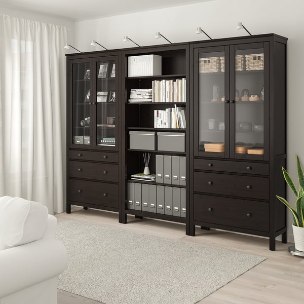 Dark brown HEMNES storage unit with shelves and drawers, next to white sofa.