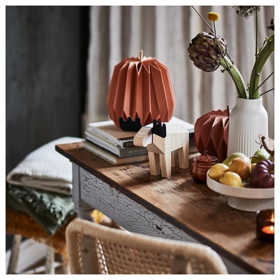 Cosy scene with wooden moose, orange & black, on a table. Vase, fruit bowl, books & chair. Moose is HÖSTAGILLE, larger size.