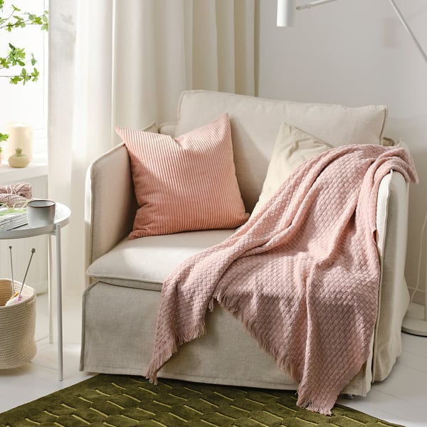 Beige HORNMAL armchair with light pink throw & pillows in cosy living space.