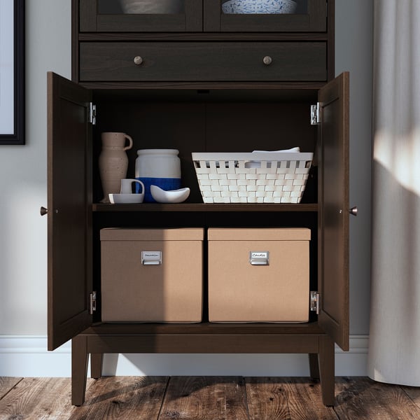 Dark wooden cabinet with two shelves. Top shelf holds vases and basket, bottom shelf has labelled storage boxes.