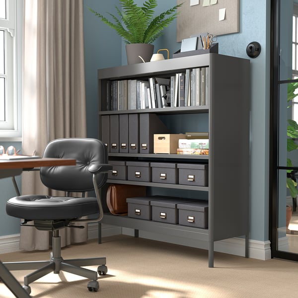 Home office with IDÅSEN black shelving unit, leather chair, books, plants, and desk.