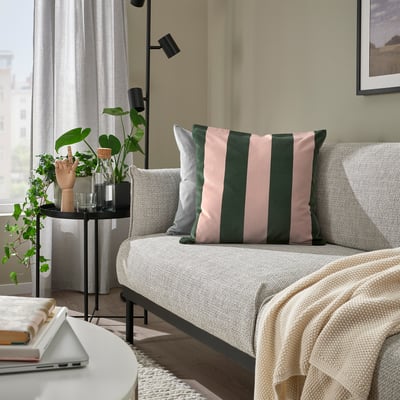 Living room with light sofa, IDGRAN pillow, plant, vase, laptop, bright, minimalist.