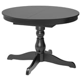 An INGATORP black round, extendable dining table with a turned leg design. Its made of materials like solid birch and particleboard.