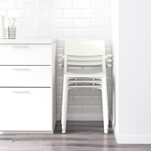 White plastic chair stacked on another, shown against white cabinets and a brick-patterned wall. Ideal for space-saving with stackable design.