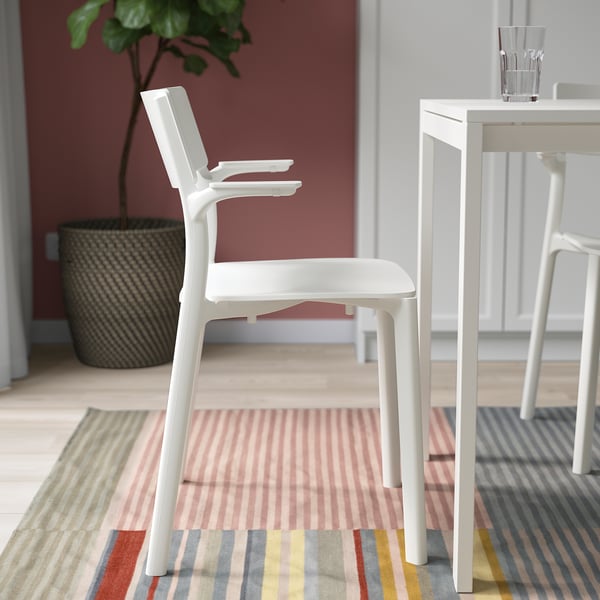 White stackable chair near a table with a glass.