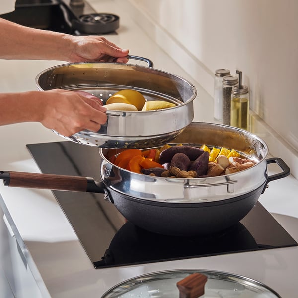 Person lifts steamer insert from pot with veggies.