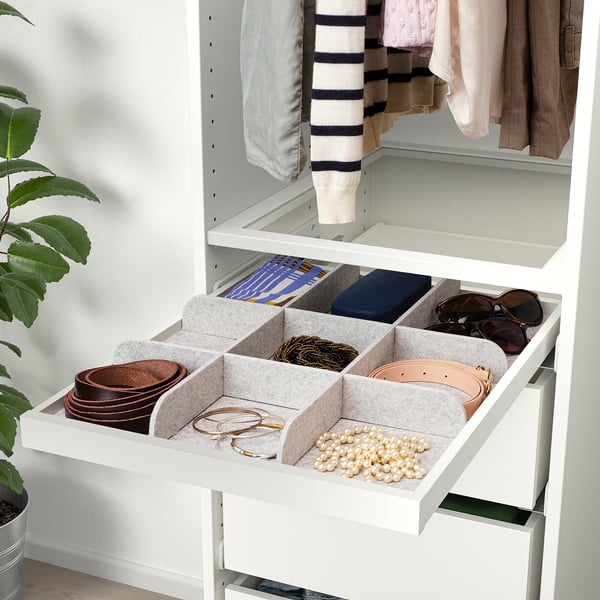 Organised drawer with felt compartments for belts, jewellery, and accessories in a white cabinet.