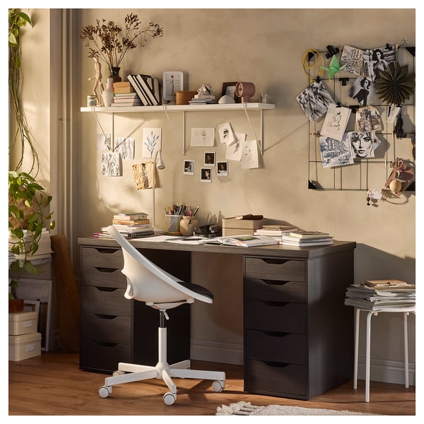 Home office with dark LAGKAPTEN desk, white chair, wall shelves, art, and plants.