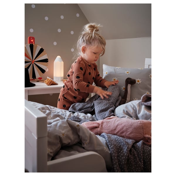 Toddler plays with blankets on bed. Lights, wheel, pillows.