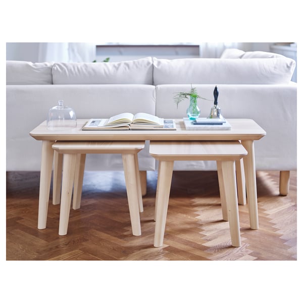 Light wooden nesting tables styled LISABO, positioned near a white couch, featuring natural wood grain and protective lacquer.