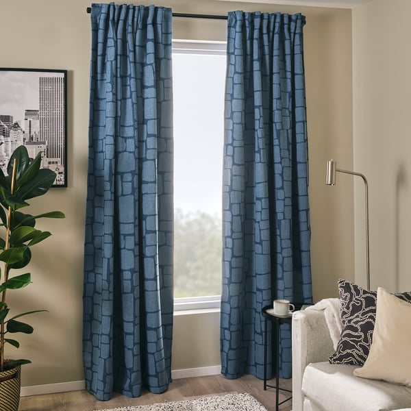 Modern blue LÖNNSTÄVMAL curtains hang near a white couch. The pattern and rich texture add elegance to the room.