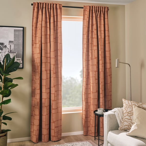 Modern living room with LÖNNSTÄVMAL red-brown curtains, white chair, plant, and city art.