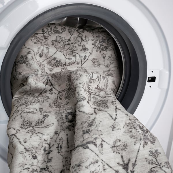 Washing machine door open with folded floral towel inside.