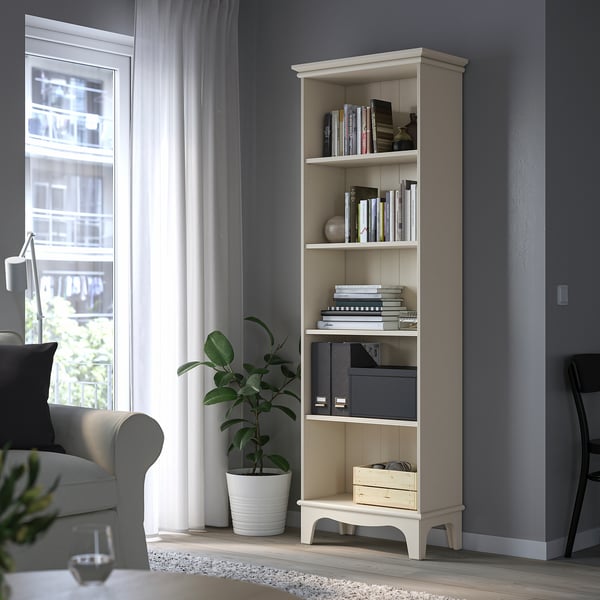 Neutral LOMMARP bookshelf against dark wall, filled with books and decor, with adjustable shelves.