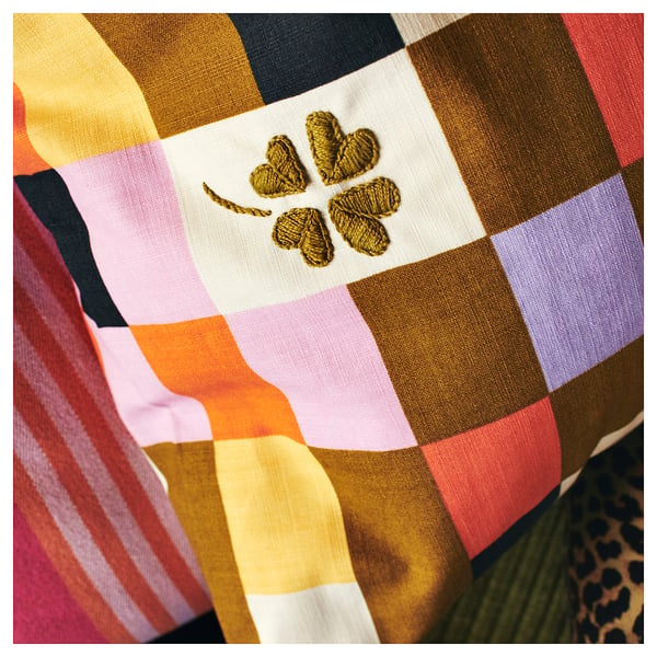 MÄVINN multi-colored check cushion with golden embroidered four-leaf clover.