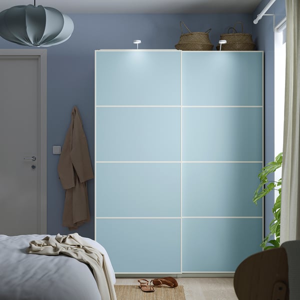 Modern bedroom with large light blue wardrobe. Includes baskets and towel hangers.
