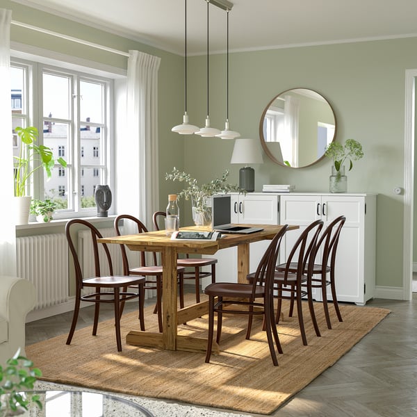 Green NACKANÄS dining table with six chairs, three lights, beige rug, white sideboard, decorative items, round mirror, light green walls.