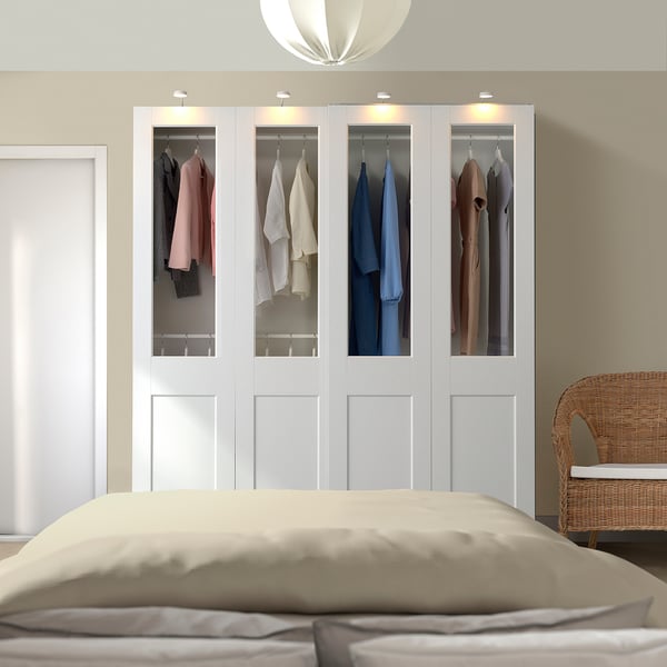 Modern bedroom with large white PAX wardrobe, beigebed, wicker chair, and soft lighting.