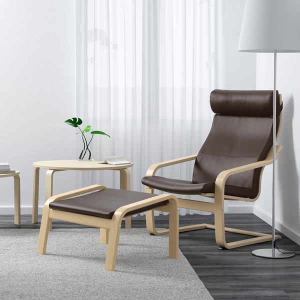 Brown POÄNG chair & footstool, lamp, side table with plant, neutral decor.