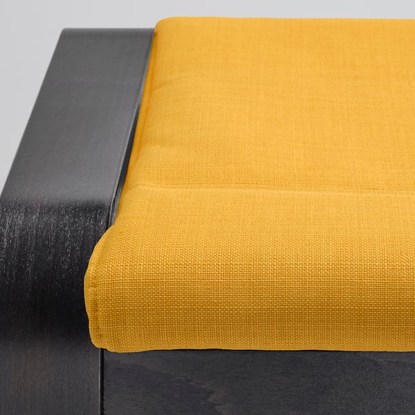 Bright yellow cushion on dark bench, showcasing POÄNGs quality fabric and sturdy design.