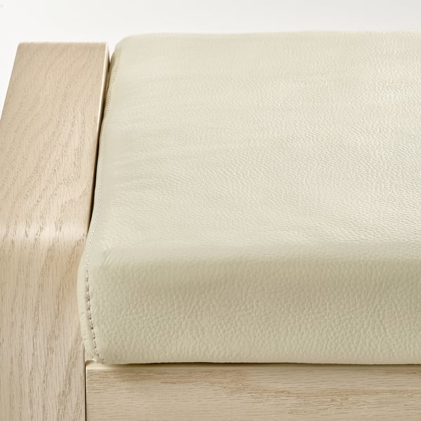 Close-up of light-colored leather upholstered cushion atop wooden chair frame, showcasing quality material and craftsmanship.