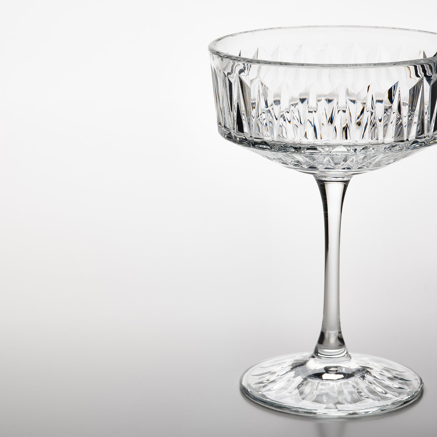 Elegant crystal glass with intricate cut patterns, standing on a reflective surface. Perfect for serving drinks.