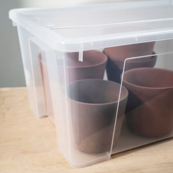 Clear plastic storage box with lid, containing four brown cups, neatly stacked on a wooden surface.