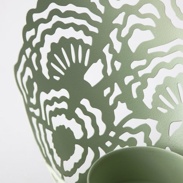 Green metal tealight holder with intricate, organic cutouts.
