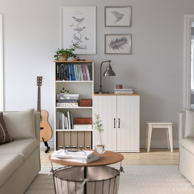 Living room with SKRUVBY sideboard, guitar, bookshelf, coffee table, two sofas, lamp, and oak-finished furniture against a light blue wall.