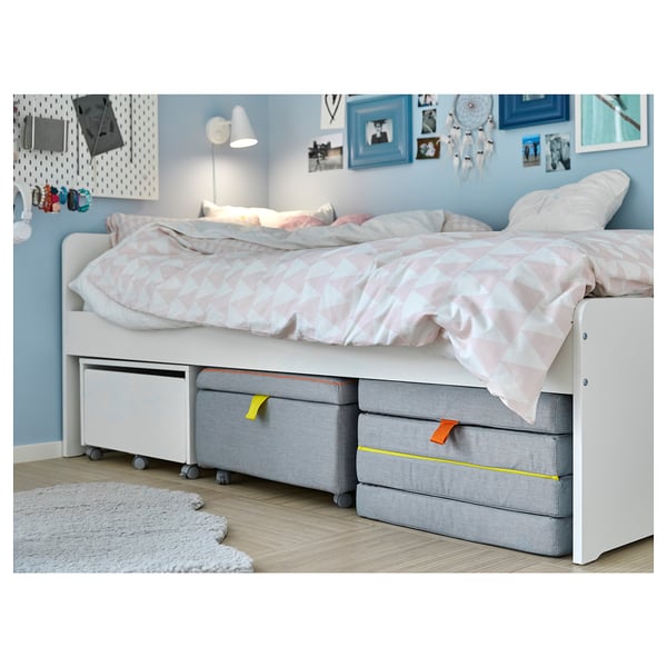 White IKEA SLÄKT kids bed with storage and fabric boxes.