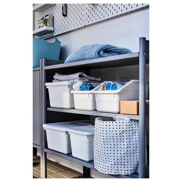 A grey metal shelf with white storage bins and folded textiles.