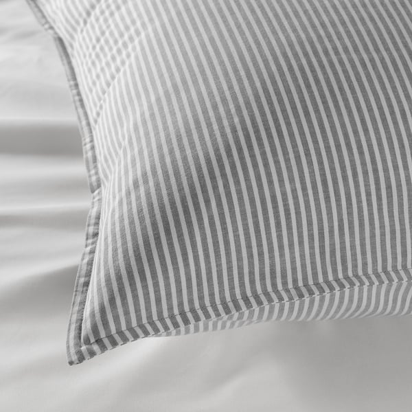 Grey striped pillow on a white surface. Close-up highlights soft, recycled cotton.