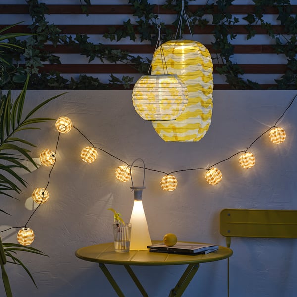 Yellow SOLVINDEN outdoor lanterns & lights decorating wall, brightening space with soft glow, combining style with function for cosy ambiance.