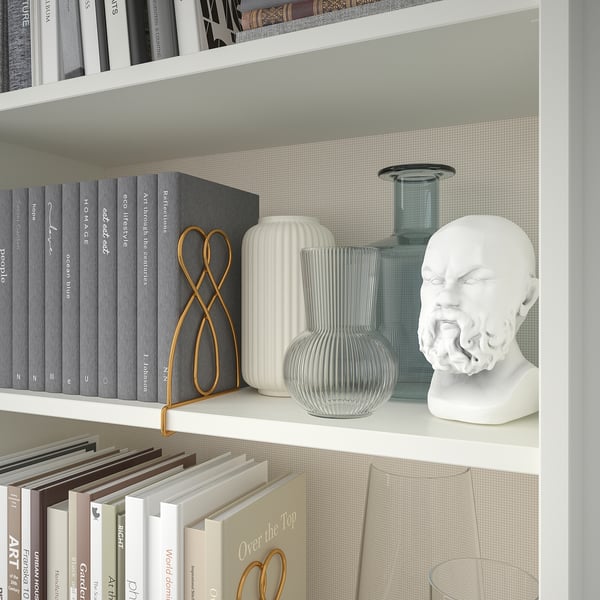 Bookshelf with books, decorative vases, and a white bust sculpture. Bookends hold books in place.