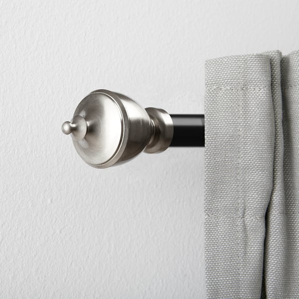 Silver curtain rod finials hold light grey curtains, enhancing window decor.