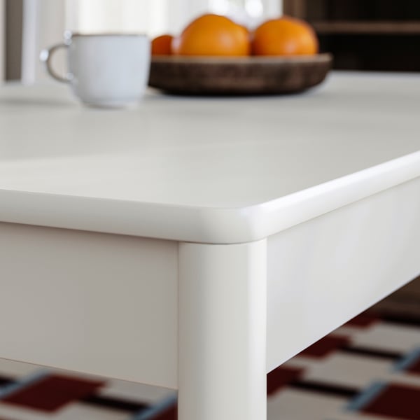 Close-up of TONSTAD tables smooth, off-white matte finish and sturdy leg design. Oranges and mug sit atop.