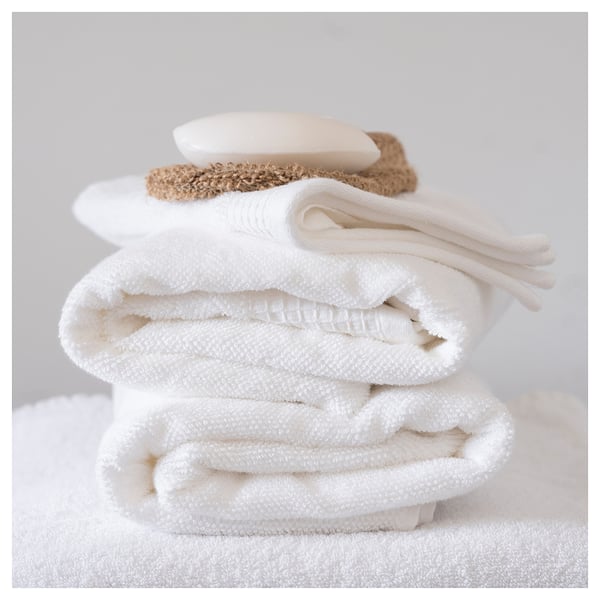 Folded stack of white towels and soap on soft grey background.