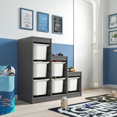 Kids room with grey TROFAST storage, holding white bins, below wall art.