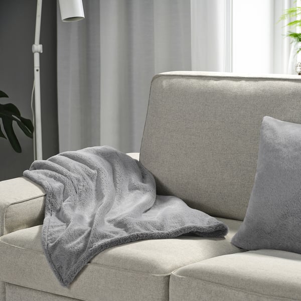 Cosy grey ULLGRIMMIA blanket on light couch, soft & recycled polyester.