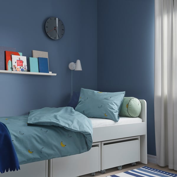 Kids room with VÄNKRETS light blue duvet, bookshelf, wall clock, and large blue wall.