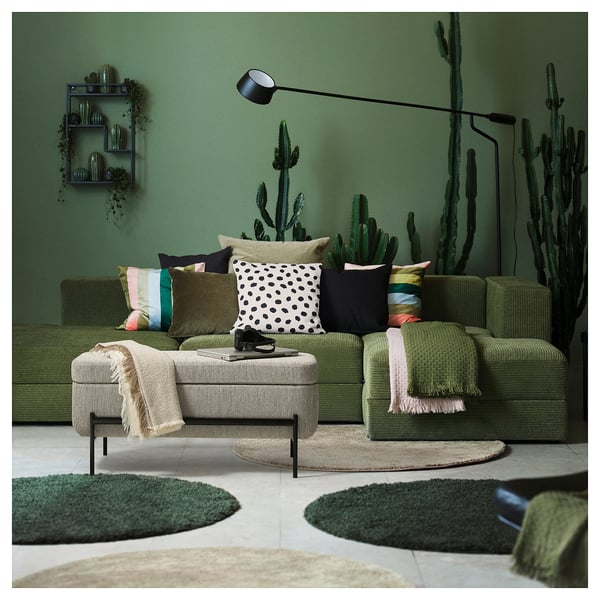 Modern living room with green VALTORP sofa, colourful pillows, cactus decorations, and a cosy rug.