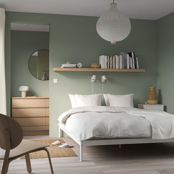 Modern bedroom: green wall, small VEVELSTAD bed, bookshelf, dresser, chair, light, basket.
