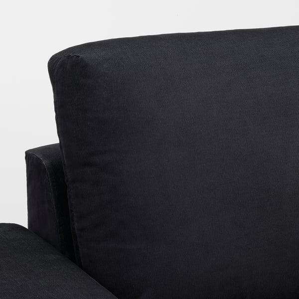 Close-up of a dark, plush sofa with a smooth, inviting texture. Curved armrests and high-quality fabric suggest comfort and durability.