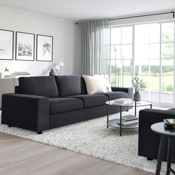 Modern living room: VIMLE grey sofa, cushions, glass side table, cactus, large window, art prints.