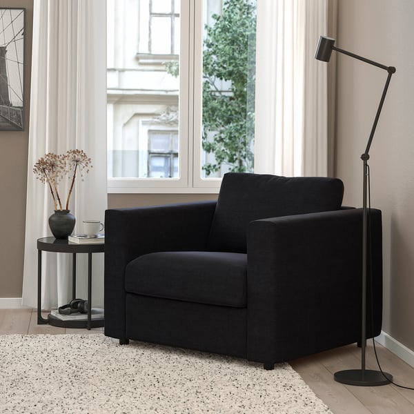 Modern living space with VIMLE armchair, windows, side table, plant, books.