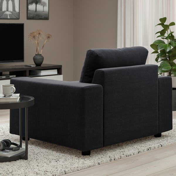 Dark grey VIMLE armchair in living room, beside small round table with mug and remote.