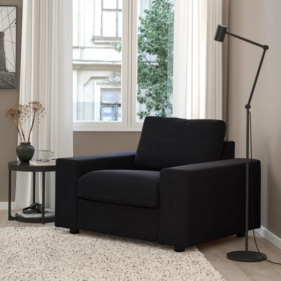 Modern living room with black VIMLE sofa, lamp, flowers, rug.